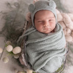 neugeborenes baby bei babyshooting mit baerenhaube