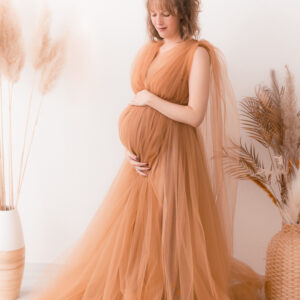 Schwangere steht mit braunem Kleid neben Pampasgras