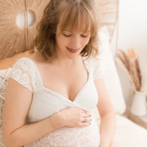 Schwangere sitzt auf Bett und schaut auf den Babybauch