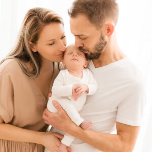 Eltern mit neugeborenem Baby küssend