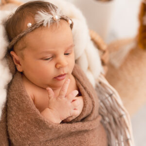 Neugeborenes Baby mit brauner Decke und Haarband