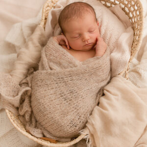 Baby in Korb mit beiger Decke gepuckt
