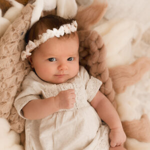 Neugeborenes Baby mit Haarkranz auf beiger Decke