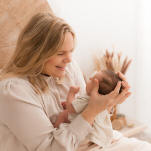glückliche Mama hält Babykopf in ihren Händen