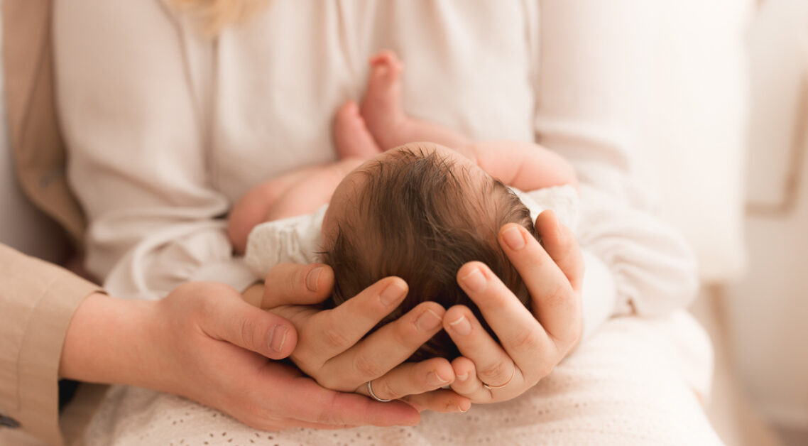 Detailaufnahme Babykopf in Mutters Hand