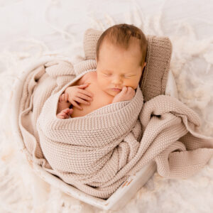 Baby in Herzschale mit Decke in beige