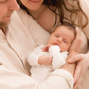 Eltern mit Neugeborenem in beiger Kledung