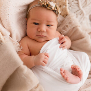 kleines Baby mit Haarkranz in weißes Tuch gewickelt